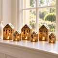 Six substantial antique gold house tealight holders styled on a minimalist white windowsill